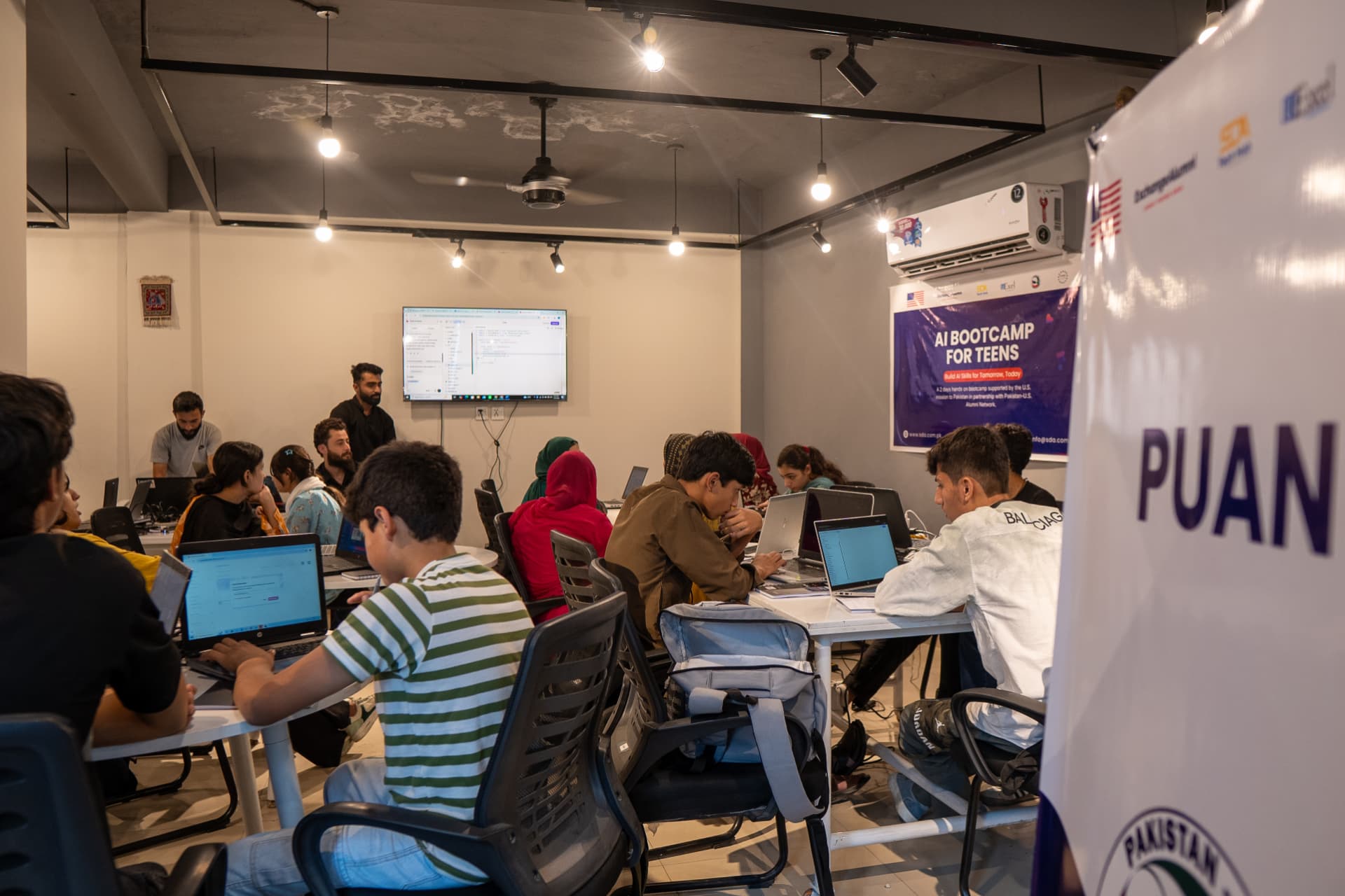 Teens working on laptops during the AI bootcamp at SDA Technology Hub