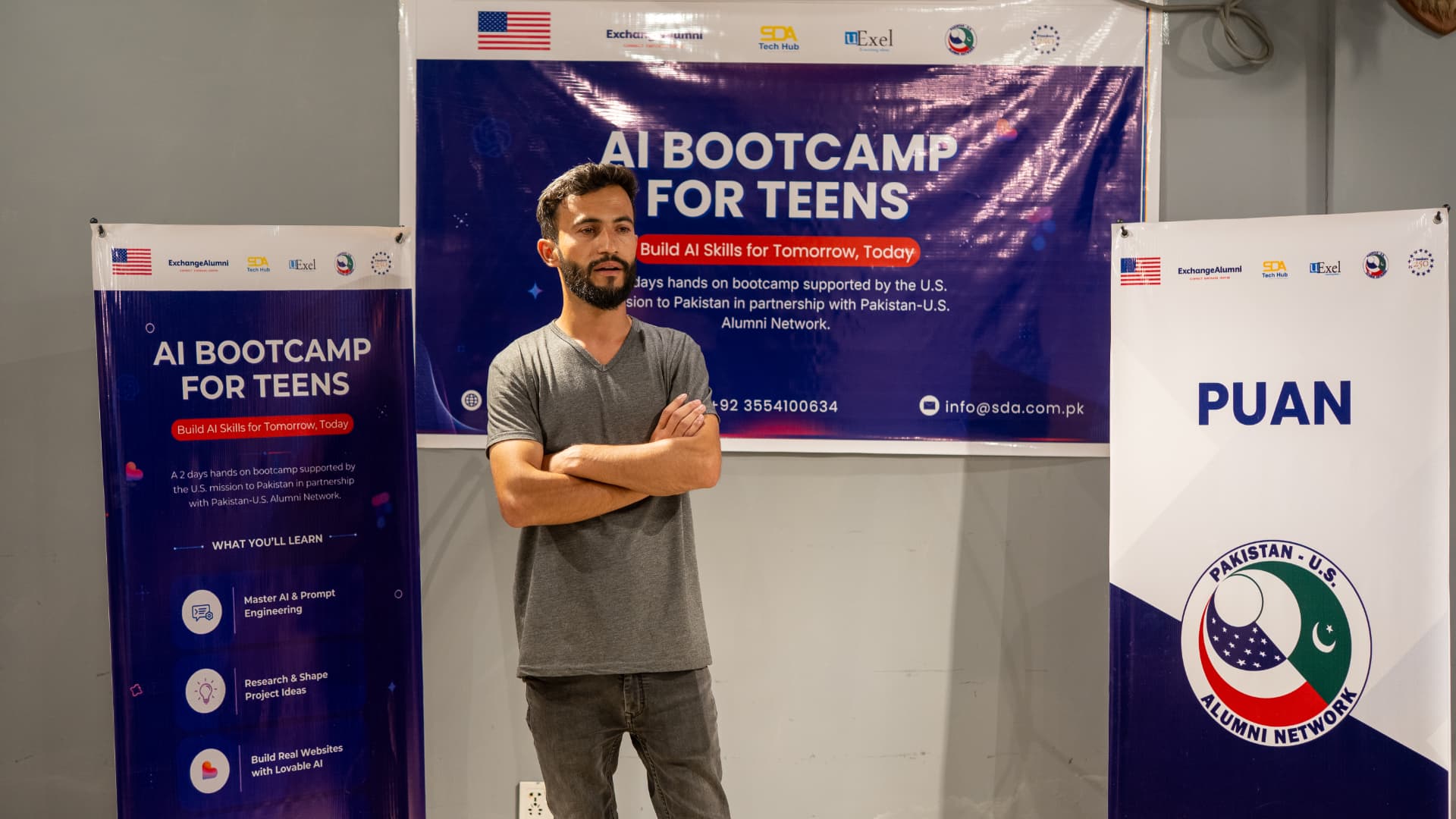 Instructor addressing the room in front of AI Bootcamp for Teens banners